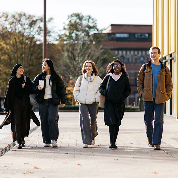 5 students walking outdoor on campus