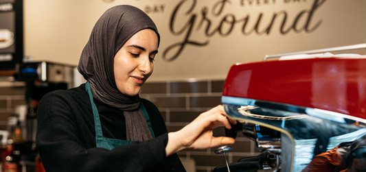 Young person pouring a coffee in a hipster-looking coffee shop