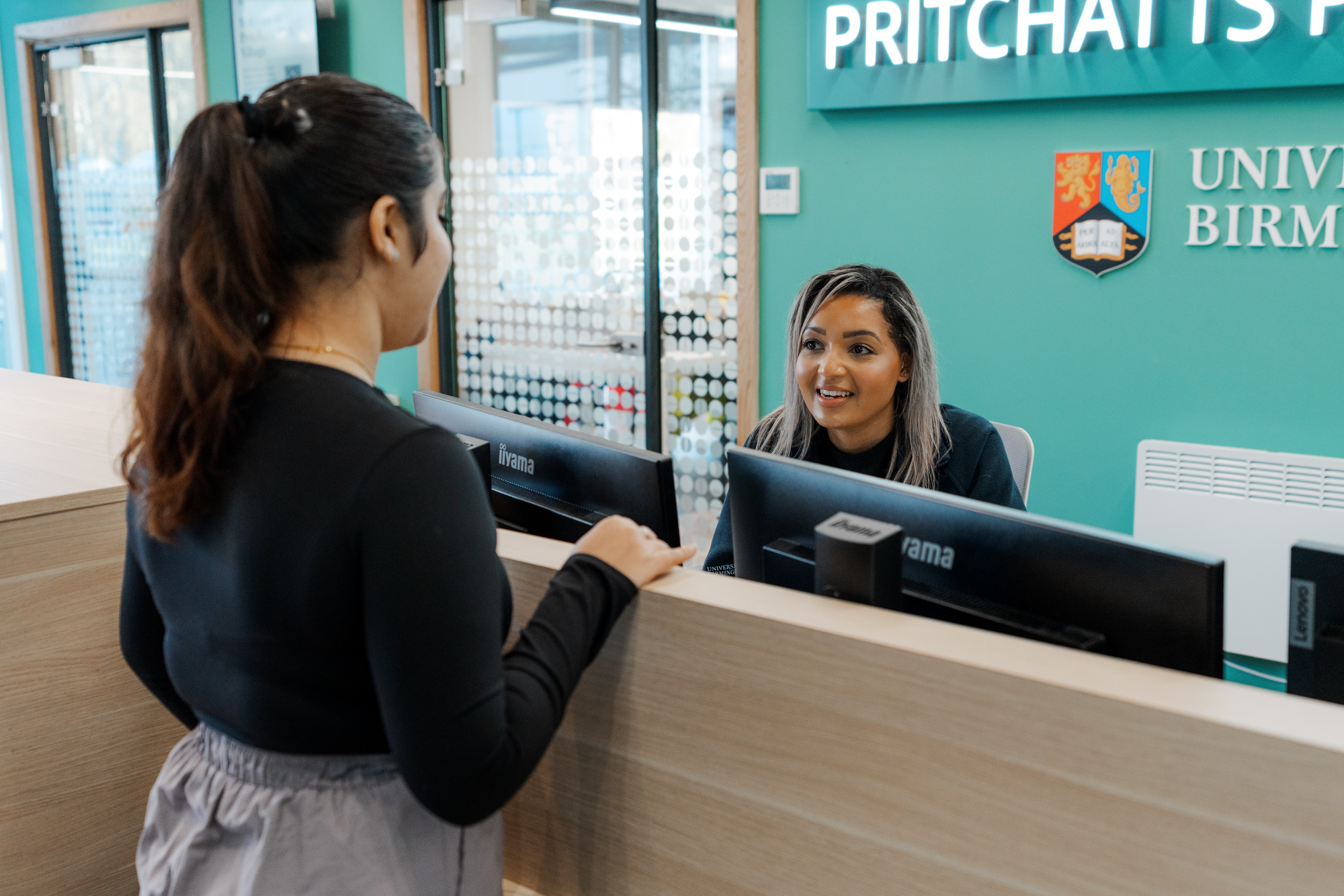 Student talking to Customer Service Manager at Pritchatts House reception.