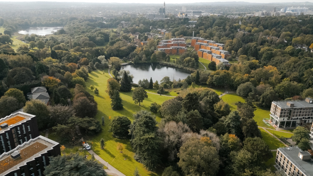 Aerial image of The Vale Village, featuring leafy green trees and a lake.