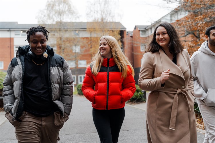 Four students walking through their village, laughing and smiling.