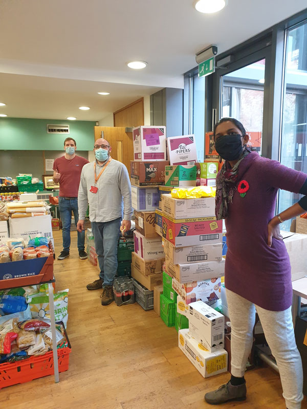 Staff in foodbank with cartons full of food and non-perishable goods