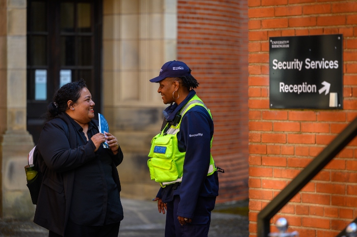 Smiling security officer talking to student on campus