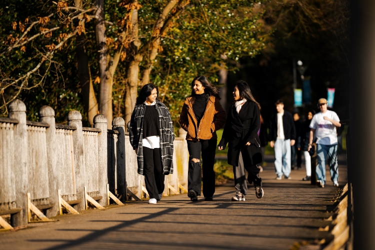 Students laughing while walking across a bridge on campus.