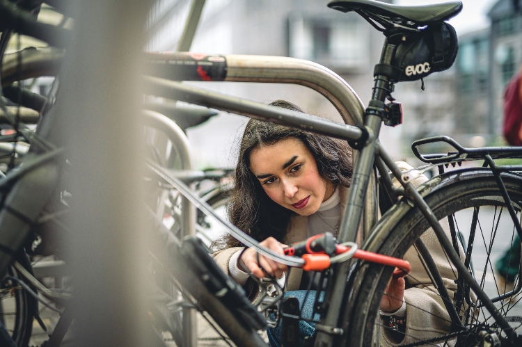 Female student securely fixing their bike with a D-lock.