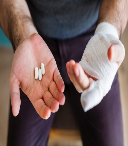Hands bandaged and holding pills