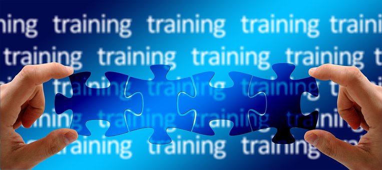 blue background with a repeated pattern of the word 'training'. in the foreground, there are two hands holding up jigsaw pieces that slot together nicely.