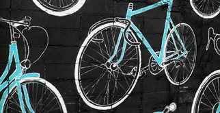 Graffiti of various turquoise-coloured bikes on a black brick wall