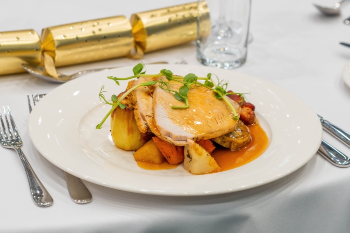 Christmas lunch with roast vegetables and turkey on a table with Christmas cracker.