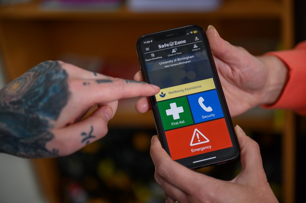 Close up of hands pointing to the SafeZone App on a phone