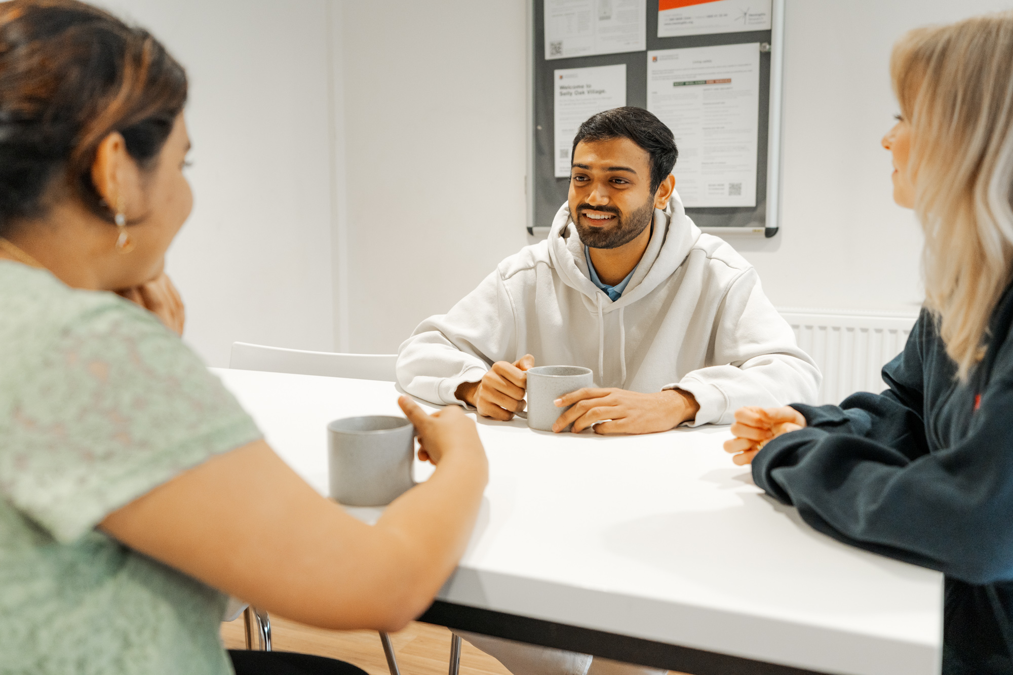 Student talking and smiling with cups of tea