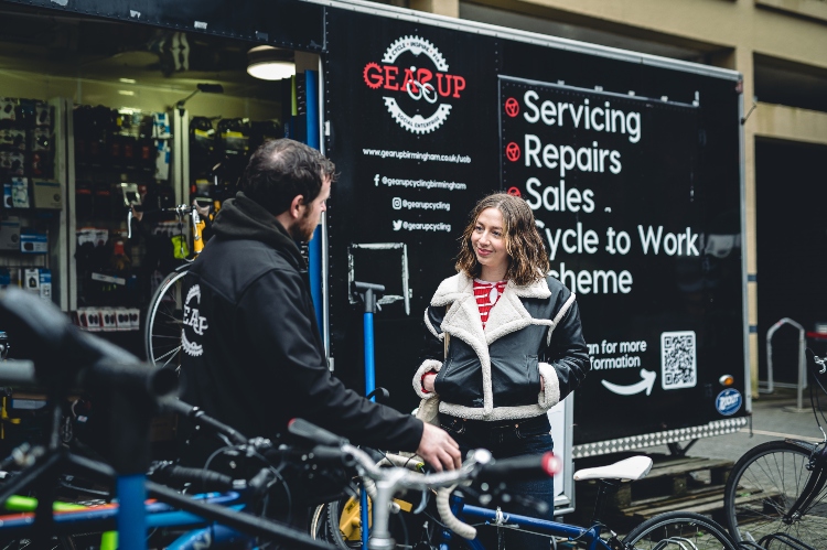 Student smiling while talking to cycling expert at campus cycle shop.