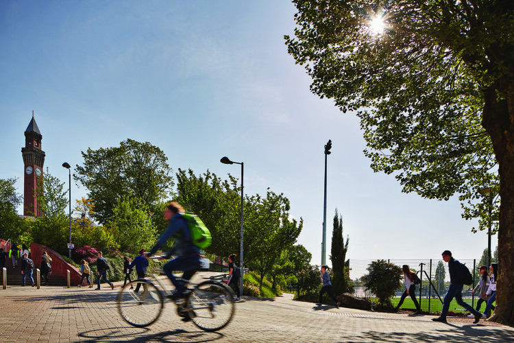 Student cycling on campus on a sunny day.