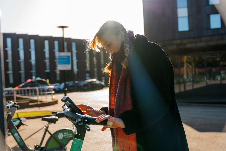 Student unlocking a Beryl scooter on campus using scooter console.