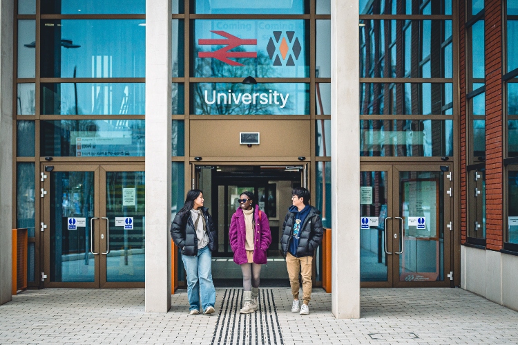 Three smiling students outside University Station