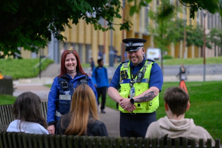 Smiling safety officers talking to students outside on campus.