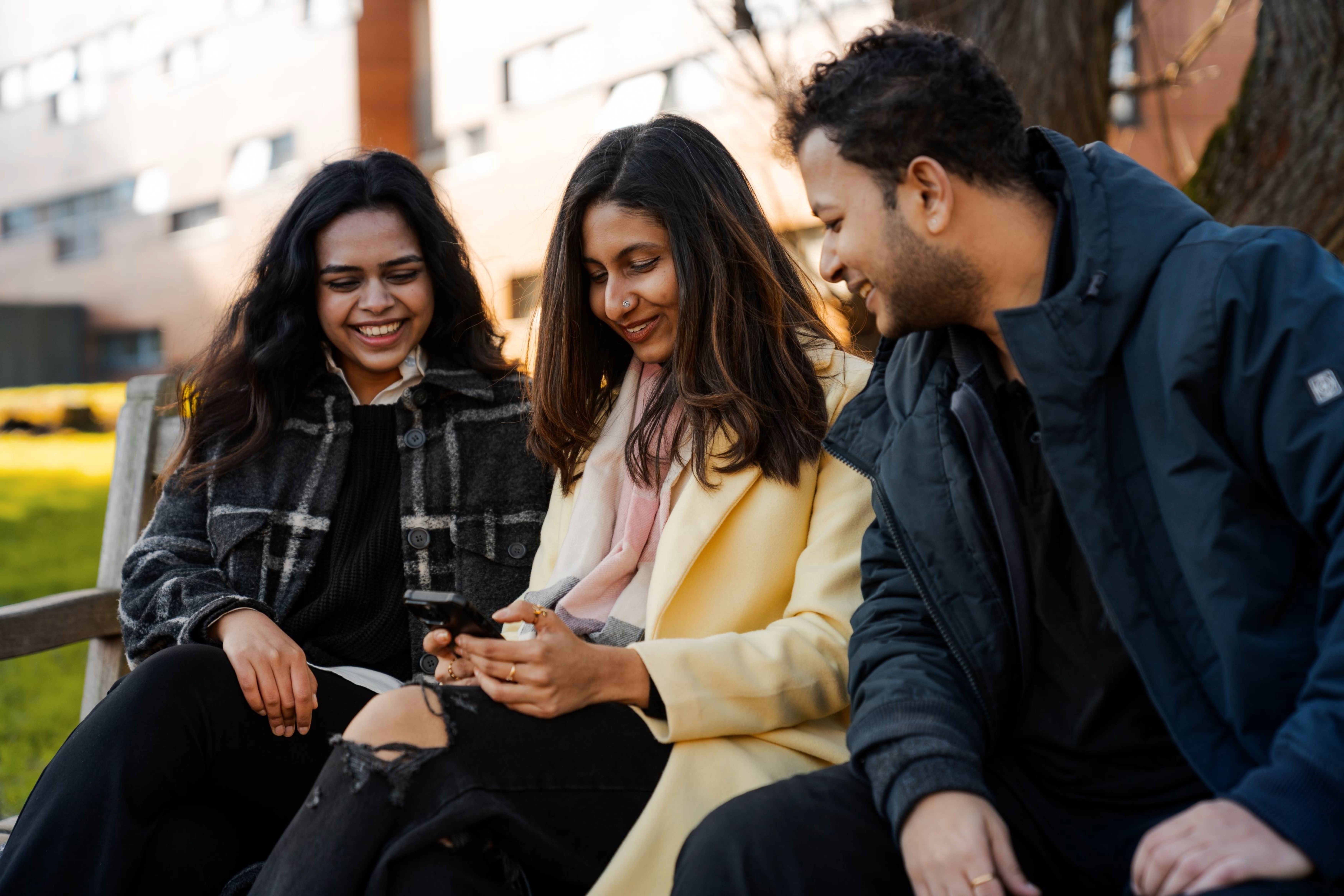 Three students sitting together looking at a phone