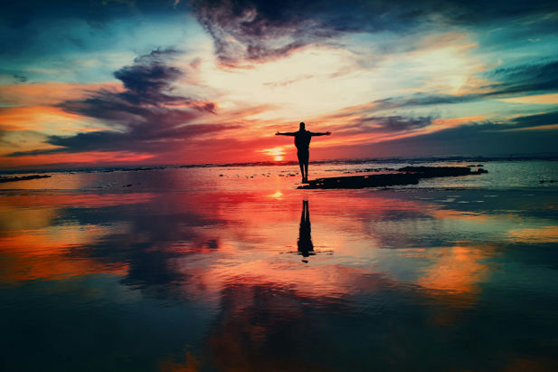 Person standing in front of colourful sunset