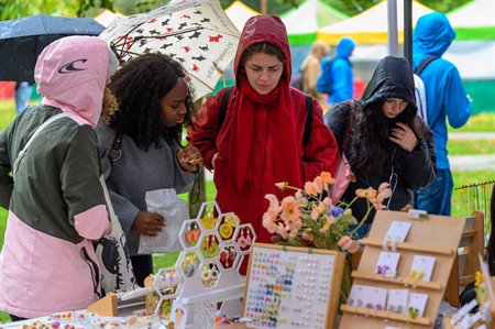 Students crowd round a market stall in raincoats.