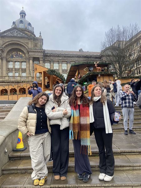 A group of four girlfriends smile at the camera.