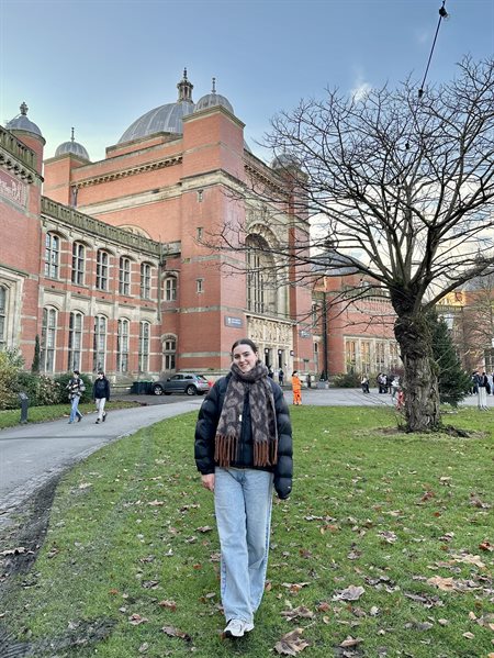 A girl smiles in front of the Aston Webb building.