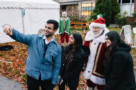 Three people smile as they take a selfie with Santa.