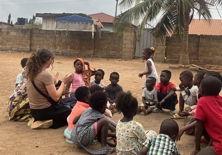 A girl sits on the floor with a group of children.