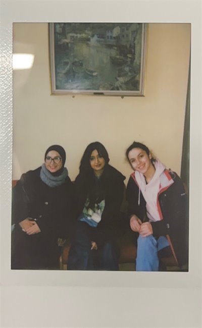 Three girls smile at the camera in a polaroid photo.