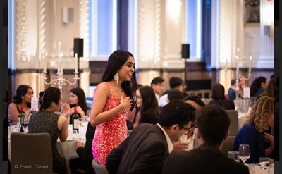 A girl in a pink dress is in the middle of the photo, surrounded by others in formal wear at a ball