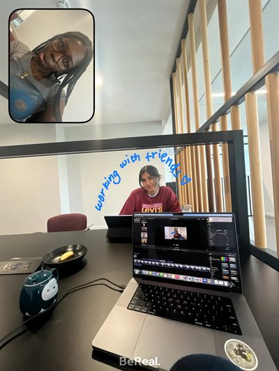 A girl smiles at the camera with a friend as they study. Some blue text reads 'working with friends'.