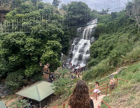 A large waterfall cuts through a lush green mountainside.