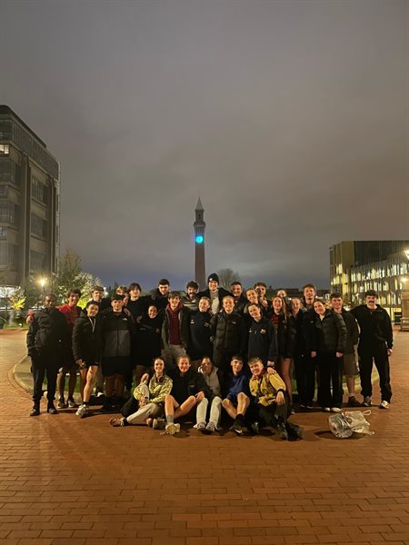 A group of aussie rules athletes stand in front of Old Joe