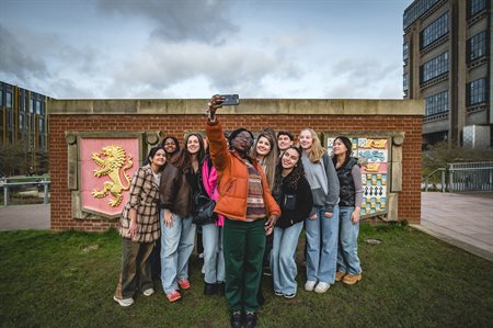 A group of students pose for a selfie by the UoB crests on main campus.