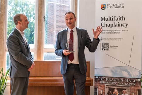 Vice Chancellor holding award and speaking at ceremony