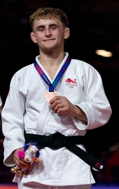 Picture of Charlie smiling in his judo clothes holding a medal