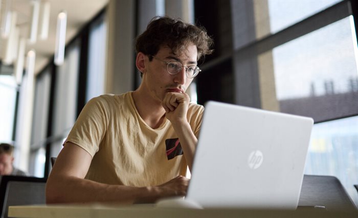 Male student sitting in front of an open laptop