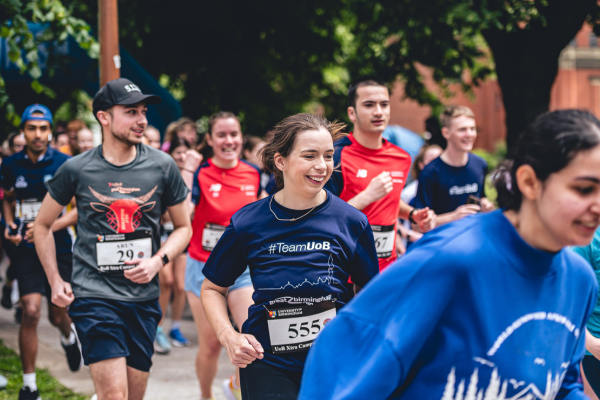 A group of students wearing sports wear are in a running pose and smiling